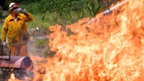 AFP A firefighter drinks water in front of a raging bushfire north of Sydney on Monday