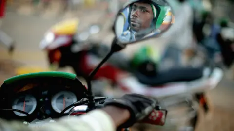 Getty Images Motorcycle taxi driver reflected in wing mirror in Kigali, Rwanda