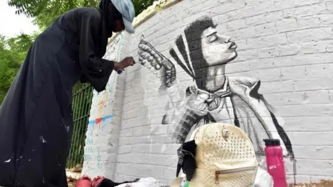 AFP A Sudanese artist paints a mural on a wall in the capital Khartoum on 22 August 2019