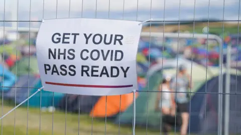 Getty/Hugh R Hastings Covid pass sign on metal fence at a festival