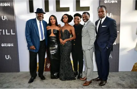 AFP Chinonye Chukwu posing in a black dress alongside other actors. There is a large billboard which says Till behind them.
