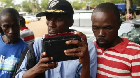 EPA Supporters of Georgia Weah's Coalition for Democratic Change party listen for results from Liberia's presidential and general elections on the radio