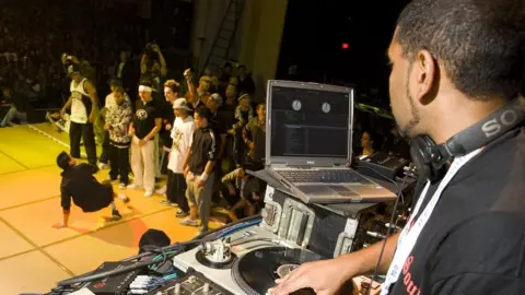 PYMCA/Avalon/Getty A DJ mixing for a dancer performing at the UK B-Boy championships in 2006