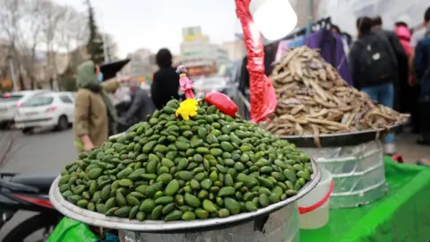 Getty Images Unripe almonds are displayed for sale as Iranian people get ready for Persian New Year