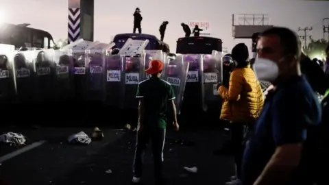 Reuters Police prevent members of the migrant caravan from passing on the Mexico-Puebla highway, in Los Reyes La Paz, Mexico, December 12, 2021.