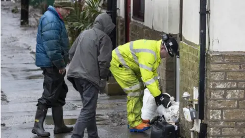 PA Media Residents lay sandbags down outside their homes in Mytholmroyd, West Yorkshire in preparation for the storm