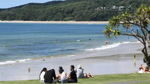 Getty Images Socially-distanced groups sit on the grass near Byron Bay