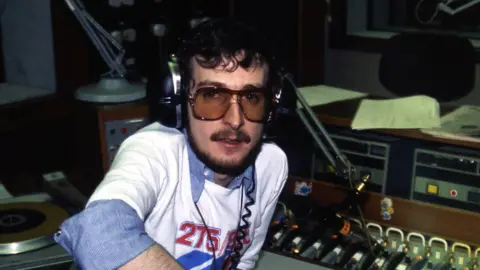 BBC Steve Wright sat behind radio microphone with headphones on