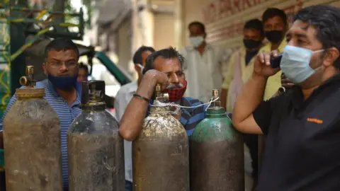 IDREES MOHAMMED/EPA People wait to fill their oxygen cylinders at an oxygen vendor in New Delhi