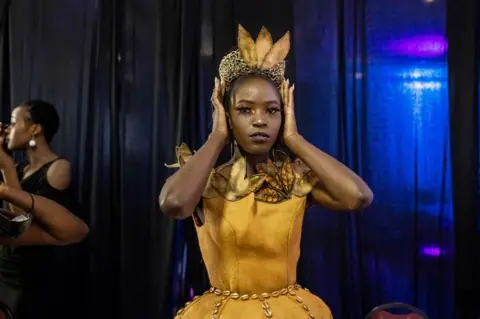 AFP A model gets ready in the backstage area during the third edition of East Africa International Fashion Week in Nairobi, on October 16, 2021. - The annual fashion event created by a former Kenyan model attracts fashion enthusiasts and buyers to see six different collections by designers from Kenya, Uganda and Tanzania.