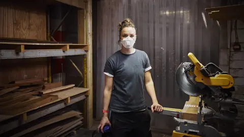 Getty Images Woman with mask working in carpentry workshop