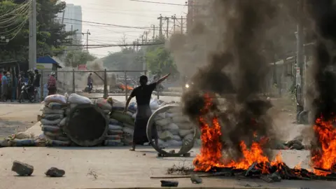 Reuters A demonstrator gestures near a barricade during a protest against the military coup in Mandalay, Myanmar March 22, 2021.