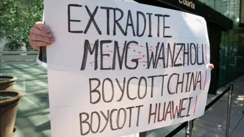 Getty Images A protester holds up a sign outside British Columbia Supreme Court where Meng Wanzhou attended a hearing on May 27, 2020 in Vancouver, Canad