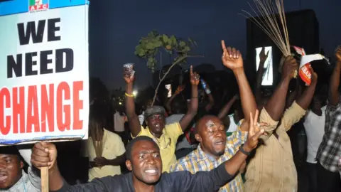 Getty Images People holding a placard saying 'We Need Change'