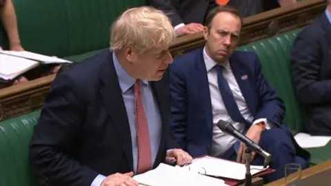 PA Media Health Secretary Matt Hancock watching Prime Minister Boris Johnson speak during Prime Minister's Questions in the House of Commons, London, both of them have tested positive for coronavirus