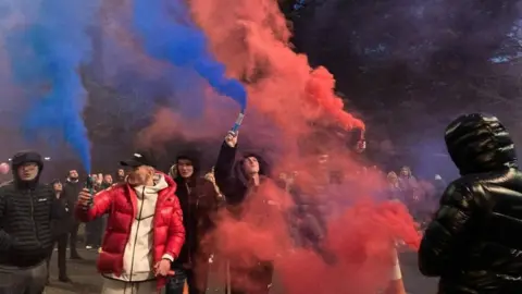 People letting off coloured flares