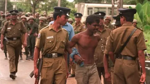 AFP Police take into custody a suspected Tamil Tiger guerrilla during a search operation near the Orugodawatte crude oil complex and the nearby Kolonnawa oil tank farm, which were allegedly blown up by suspected Tamil Tiger guerrillas in Colombo 20 October.