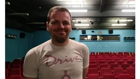 Arun Kapur A man standing in front of an empty cinema