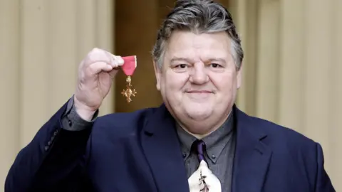 PA Media Robbie Coltrane and his OBE in 2006