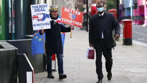 Getty Images Kwasi Kwarteng walks by Brexit protestor in London