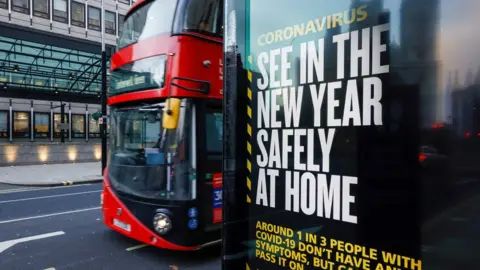 Reuters A bus drives past a British governments advertisement sign reminding people to stay at home in the New Year, near the Houses of Parliament, in London