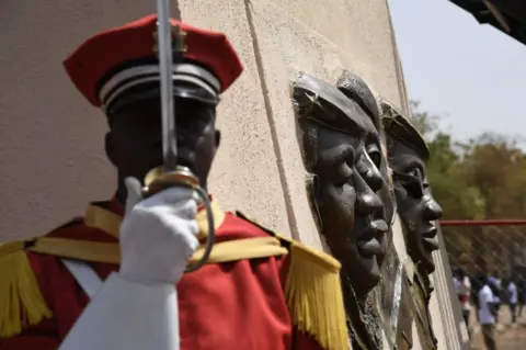 AFP A soldier stands under the bronze statue of Burkina Faso's former President Thomas Sankara on 2 March 2019.