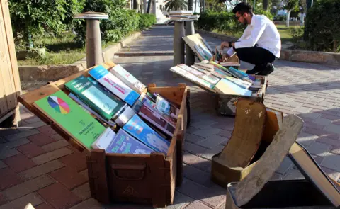 Reuters A man looks at books in boxes that were used to store ammunition during the war, in Misrata, Libya, March 13, 2018.