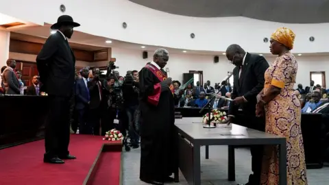 Reuters Riek Machar (r) takes the oath of office in front of President Salva Kiir and Chief Justice Chan Reech Madut, at the State House in Juba, South Sudan, February 22, 2020