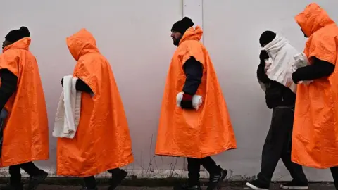 Getty Images Migrants standing in a queue waiting to be processed in Kent.