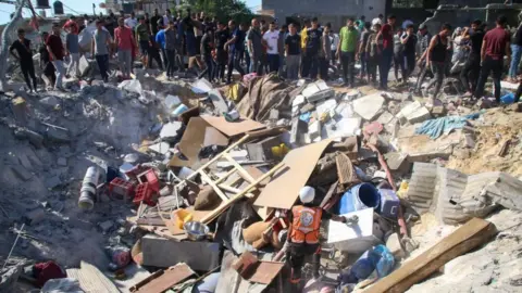 Getty Images Palestinians in a crater in Gaza