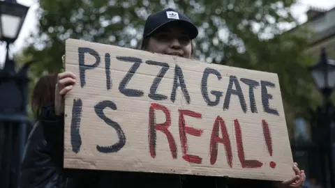 Getty Images A protestor holds a sign during a "Save our Children" rally outside Downing Street on October 10, 2020 in London