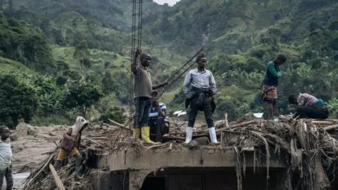 AFP Residents of Nyamukubi stand amidst rubble after heavy flooding in eastern Democratic Republic of Congo, on May 6, 2023