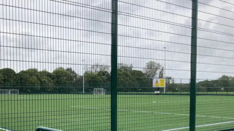 A new 3G sports pitch with large green fence and floodlights.