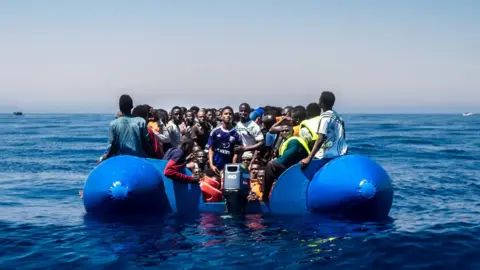 Getty Images Refugees wait to get on onboard the rescue vessel Golfo Azzurro by members of the Spanish NGO Proactiva Open Arms, after being rescued from a wooden boat sailing out of control in the Mediterranean Sea near Libya on Thursday, June 15, 2017