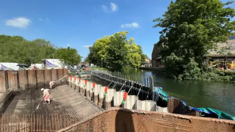 BBC Engineers work below a barricade holding back the river