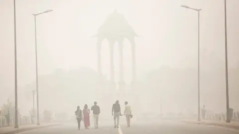 People walk near India gate amid heavy dust and smog November 7, 2016 in Delhi