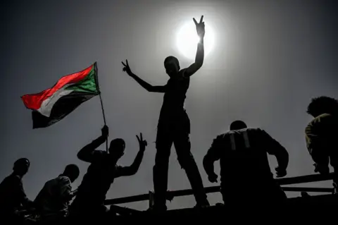 AFP Sudanese protestors wave flags and flash victory signs as they continue to protest outside the army complex in the capital Khartoum on 17 April 2019.