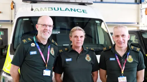 NHS Charities Together Chris Lye, Lisa Kenyon and Paul Cherry standing in front of an ambulance