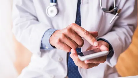 Getty Images doctor holding smart phone