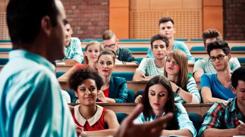 Getty Images Lecturer and students in a lecture theatre