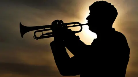 Ministry of Defence Solder plays last post against backdrop of setting sun