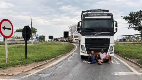 Reuters Demonstrators sit in front a truck as they block federal roads during a protest on the day after the Brazilian presidential election run-off, in Varzea Grande in Mato Grosso state, Brazil, October 31, 2022.