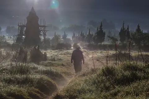 Garry Lotulung / AFP A tourist walks past the Setiaku temple on a foggy morning in the Dieng mountain area in Banjarnegara, Central Java province, Indonesia, on 6 August 2022