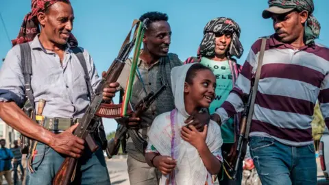 AFP Ethiopian Amhara fighters in Mai Kadra, Tigray region, posing for a photo with a young girl - 21 November 2020