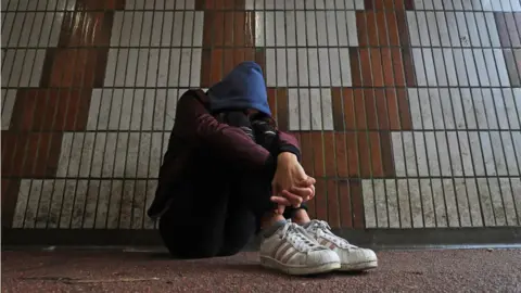 Gareth Fuller/PA Media a child sitting down, clutching themselves