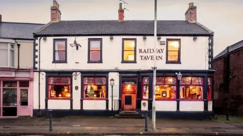 Historic England An old pub looking inviting with lights on in the windows