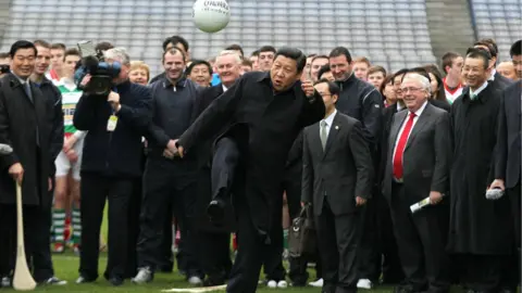 Getty Images Xi Jinping kicking a football in front of a crowd