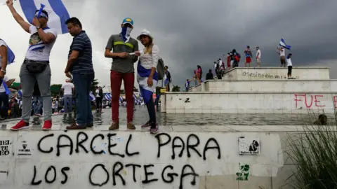 Getty Images Demonstrators stand above graffiti reading "Jail for the Ortegas" in Managua on May 26, 2018