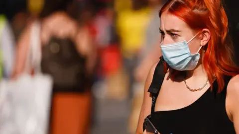 Getty Images Woman on the street wearing a facemask