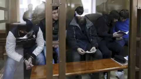 Reuters The five defendants in a glass cage in Moscow's court